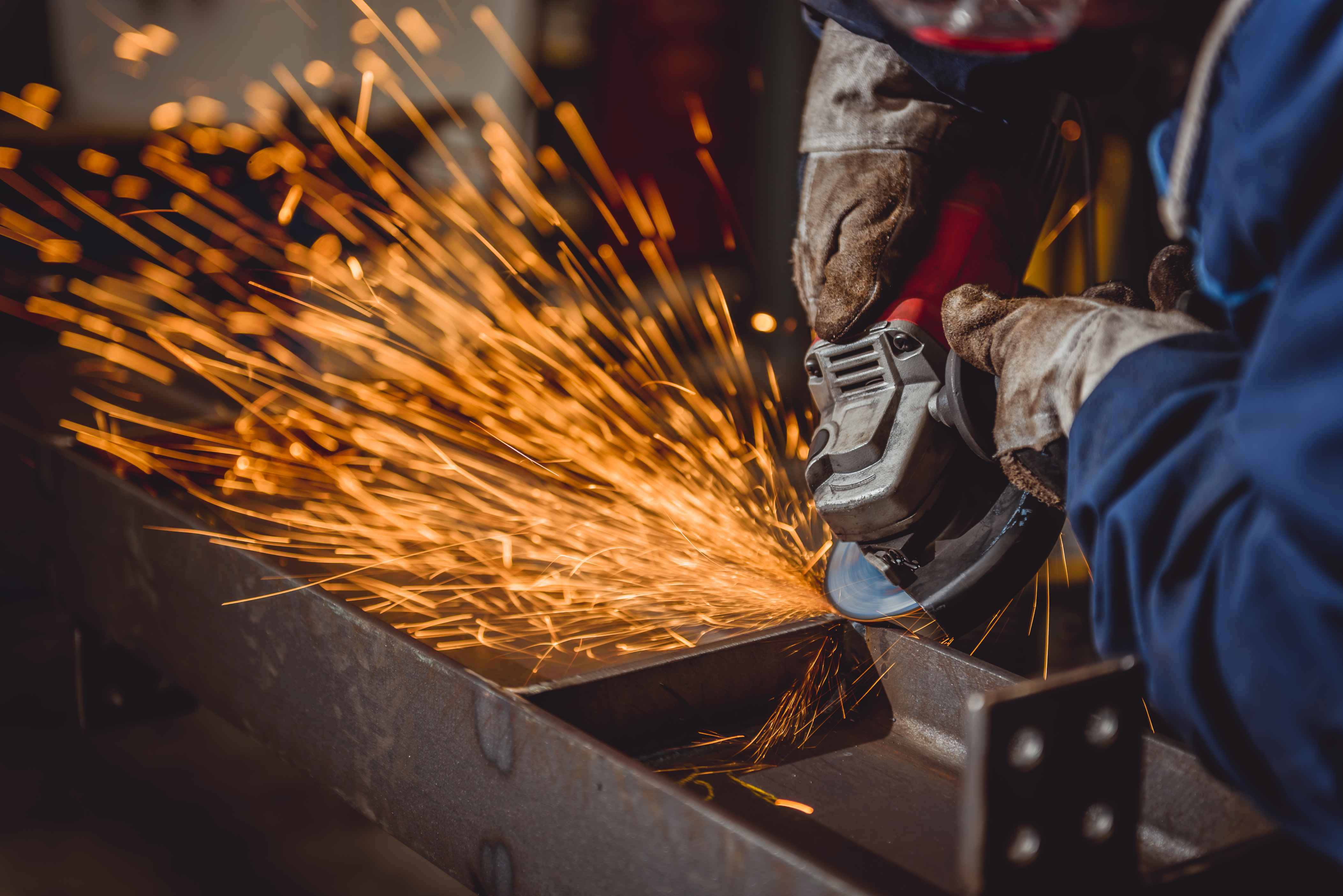 Image of a steel fabricator using an angle grinder on angle iron,